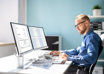 Metier Informaticien - Commercial faisant des calculs devant des ecrans d'ordinateur - numerique