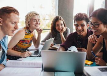 Groupe d'etudiants souriants / Equipe de jeunes salaries Start up - stagiaires travaillant autour d'un ordinateur