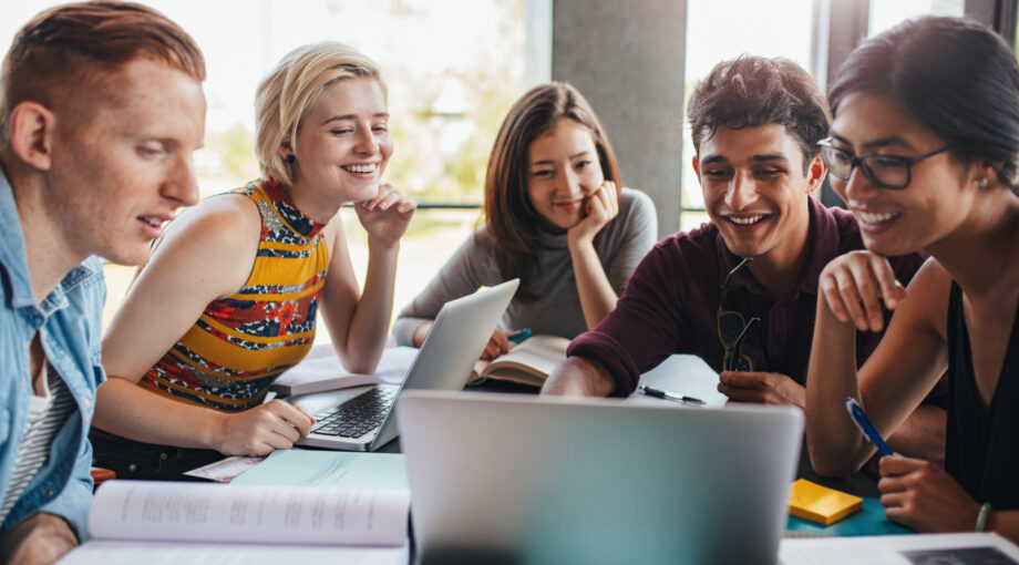 Groupe d'etudiants souriants / Equipe de jeunes salaries Start up - stagiaires travaillant autour d'un ordinateur